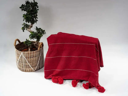 Plaid rouge avec des bandes dorées et des pompons noirs